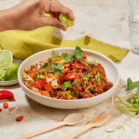 Mexican burrito bowl, hand squeezing lime over the top